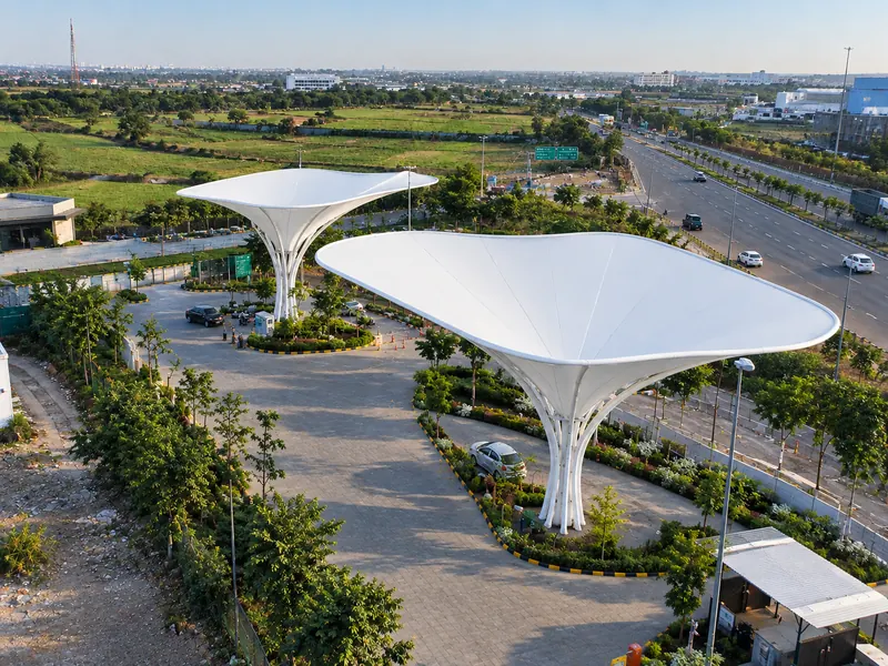 Two inverted umbrella tensile canopies over a highway-side forecourt